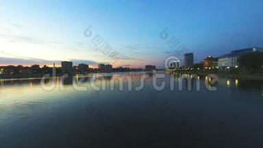 伏尔加河上美丽的日落。 水岸的模糊镜头打开了路灯和红绿灯